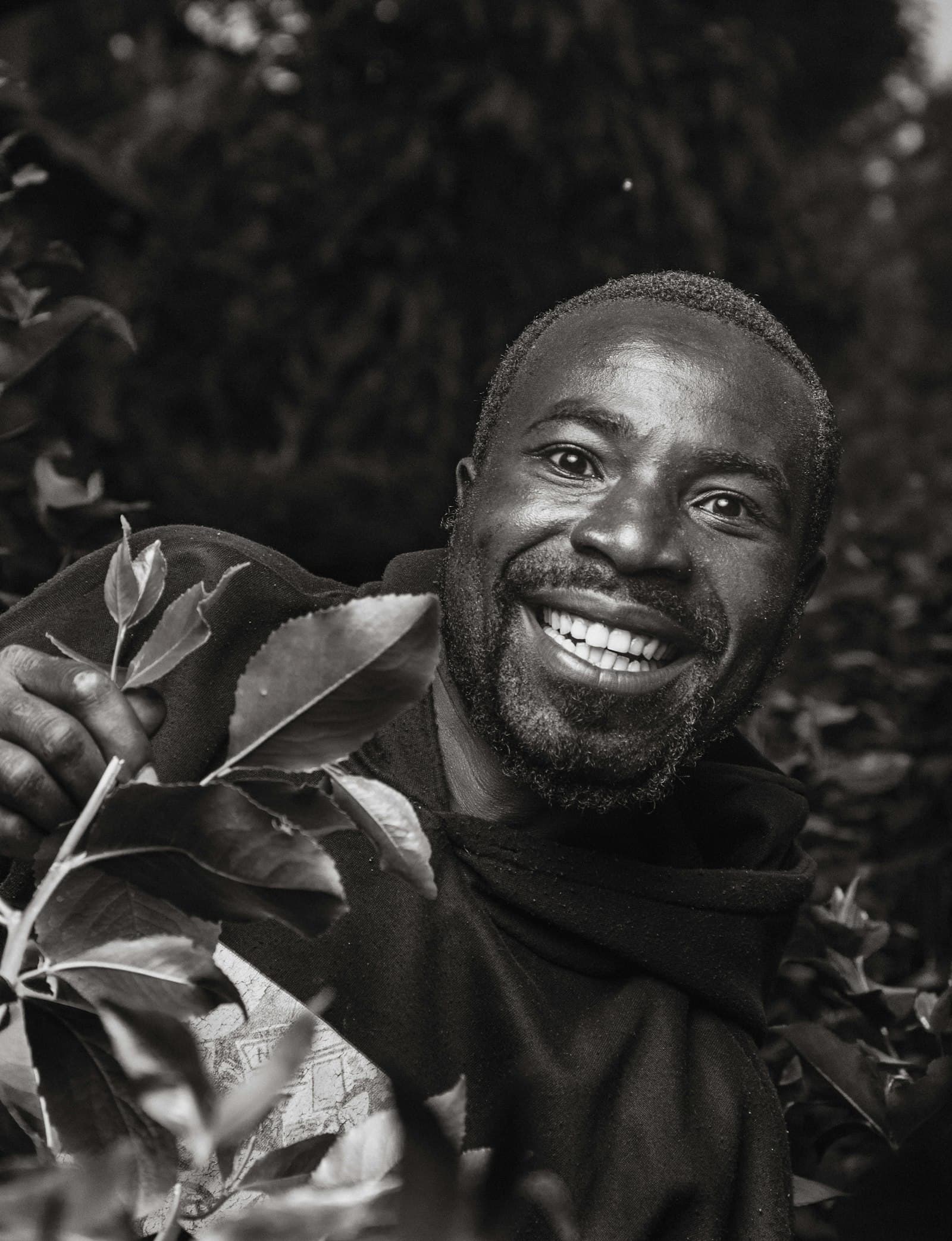 A smiling man holding a leafy green branch